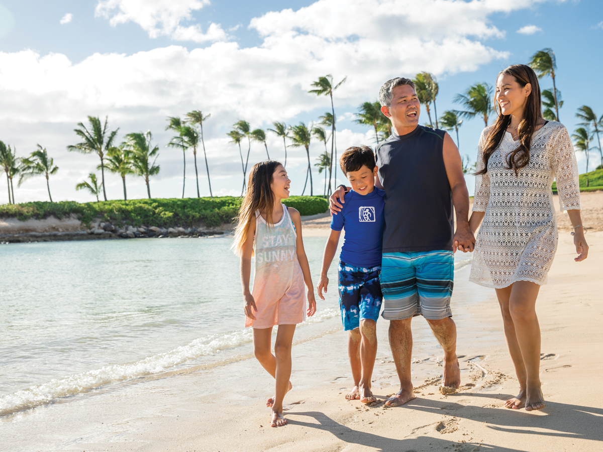 Family enjoying walking on tropical island beach together
